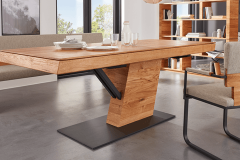 Massiver Esstisch aus Holz mit auffälligem, modernem Mittelfußdesign und schwarzem Metallakzent; arrangiert in einem eleganten Esszimmer mit passenden Möbeln und dekorativen Details.