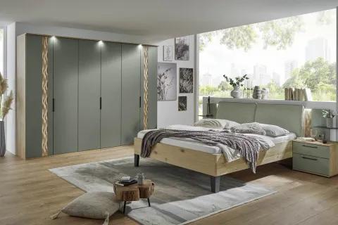Modernes Schlafzimmer mit einem Bett aus Holz und gepolstertem Kopfteil, einem großen Kleiderschrank mit grünen Türen und dekorativen Akzenten sowie einer breiten Fensterfront mit Blick auf eine grüne Landschaft.