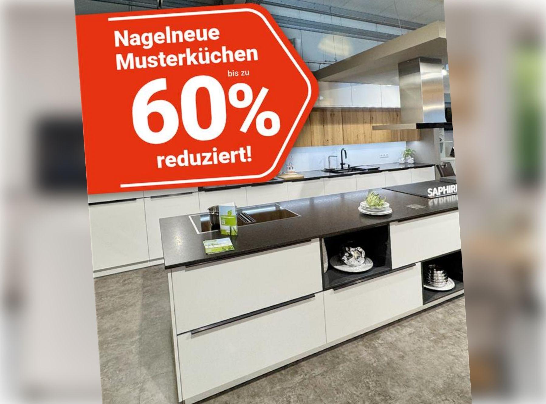 Weiße Ausstellungsküche mit dunkler Arbeitsplatte und Holzrückwand im Melber-Küchenstudio. Rotes Aktionslabel: „Nagelneue Musterküchen bis zu 60 % reduziert!"