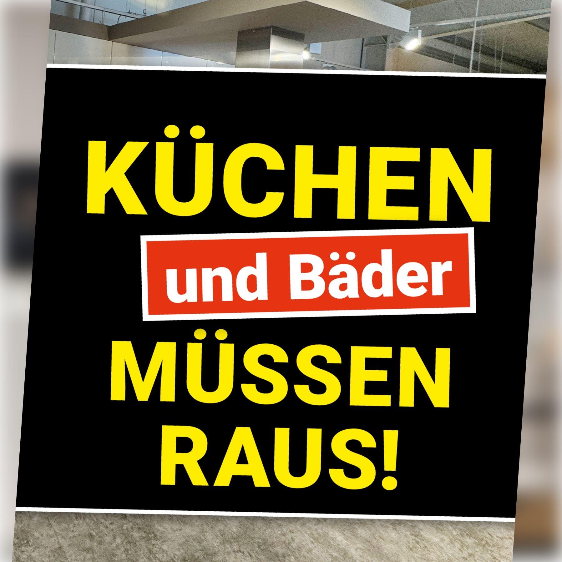 Schwarzes Aktionsbanner mit gelber Schrift vor leerem Ausstellungsraum. Schriftzug: „Küchen und Bäder müssen raus!"