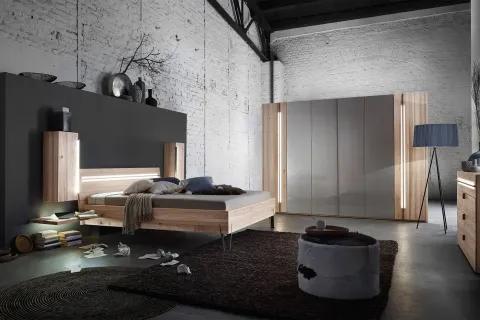 Modernes Schlafzimmer mit weißer Ziegelwand, beleuchtetem Holz-Doppelbett und grauem Kleiderschrank mit Holzakzenten.