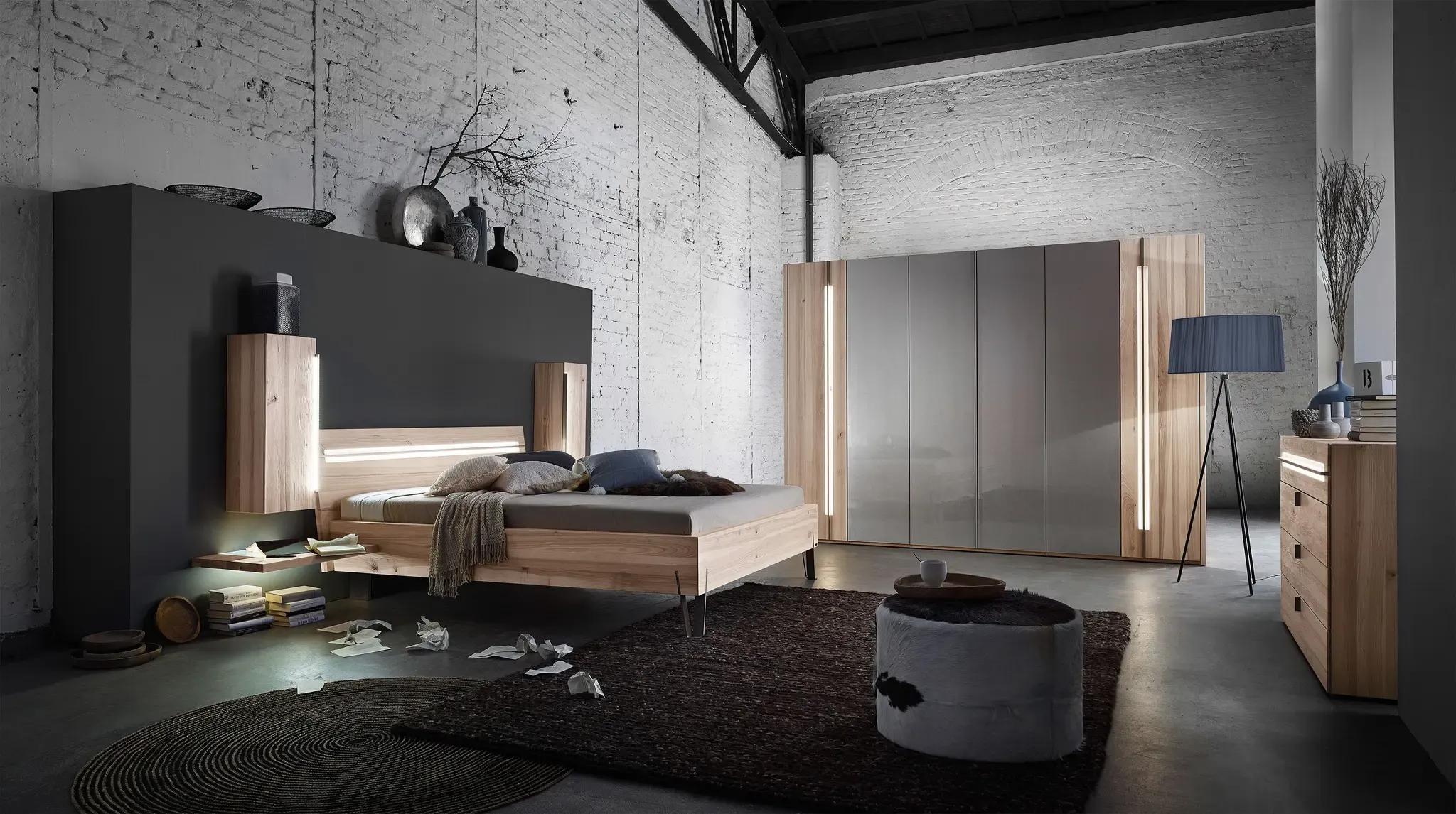 Modernes Schlafzimmer mit weißer Ziegelwand, beleuchtetem Holz-Doppelbett und grauem Kleiderschrank mit Holzakzenten.