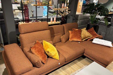 Rostrote Couchgarnitur mit modernen gemusterten Kissen, kombiniert mit einem Holztisch und runden Beistelltischen auf einem dunklen Teppich.