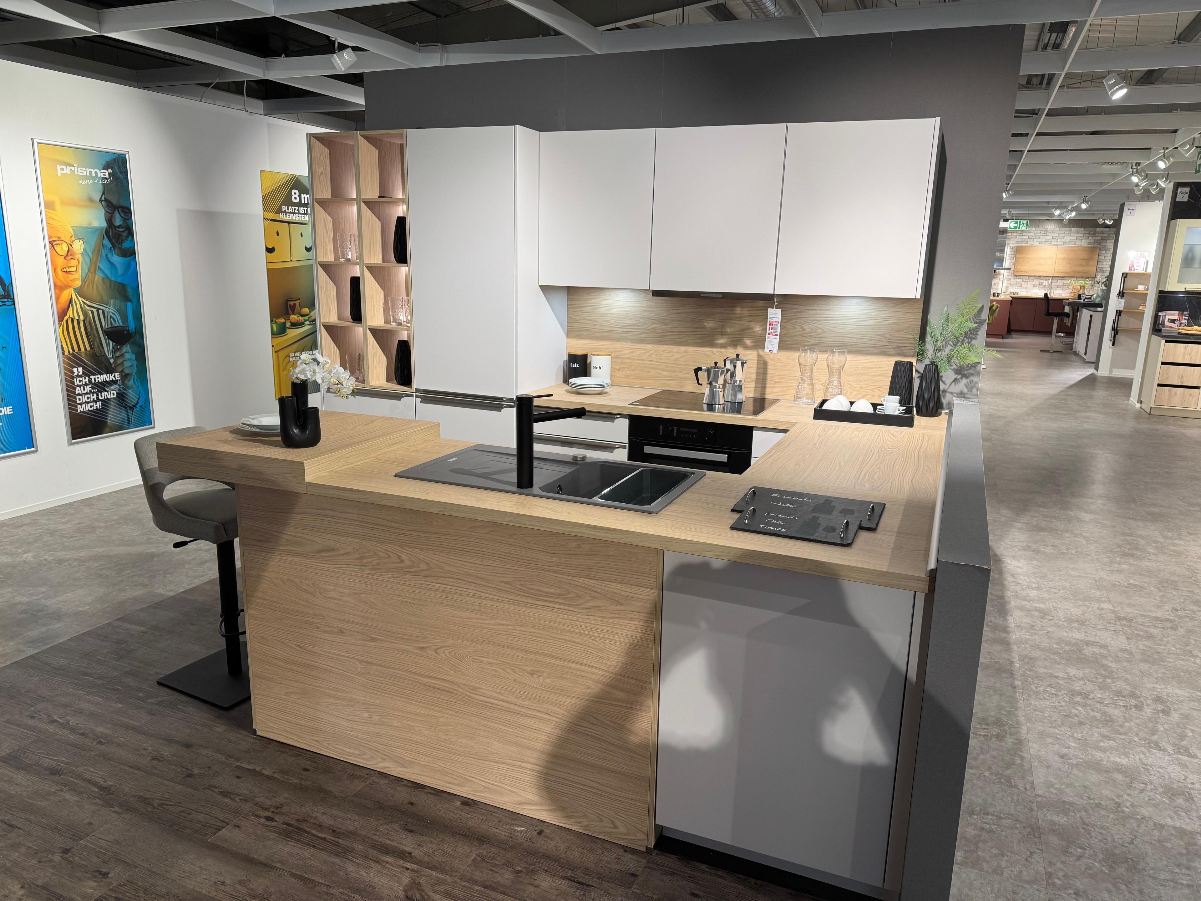 Moderne Küche in Weiß und Grau mit großer Kochinsel in Holzoptik, integriertem Kochfeld mit Downdraft-Abzug, schwarzer Armatur und offenem Holzregal