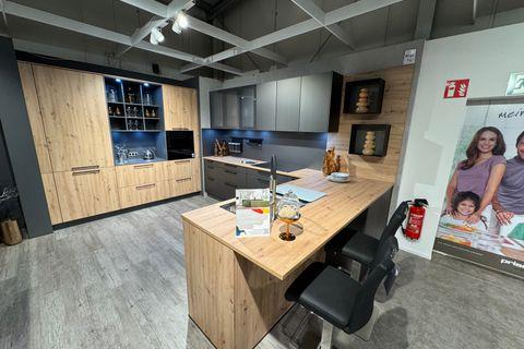 Moderne Küche in Anthrazit und Eiche-Optik mit Kochinsel, Holzarbeitsplatte, Bartresen mit Hockern, beleuchtetem Weinregal und grifflosen Oberschränken