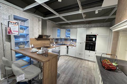 Weiße Landhausküche mit Rahmenfronten, Holzarbeitsplatte und Nischenrückwand in Eiche, Bartresen mit Polsterhockern, beleuchtetem Designregal mit blauer LED-Beleuchtung und Hochschrank mit Einbaugeräten.