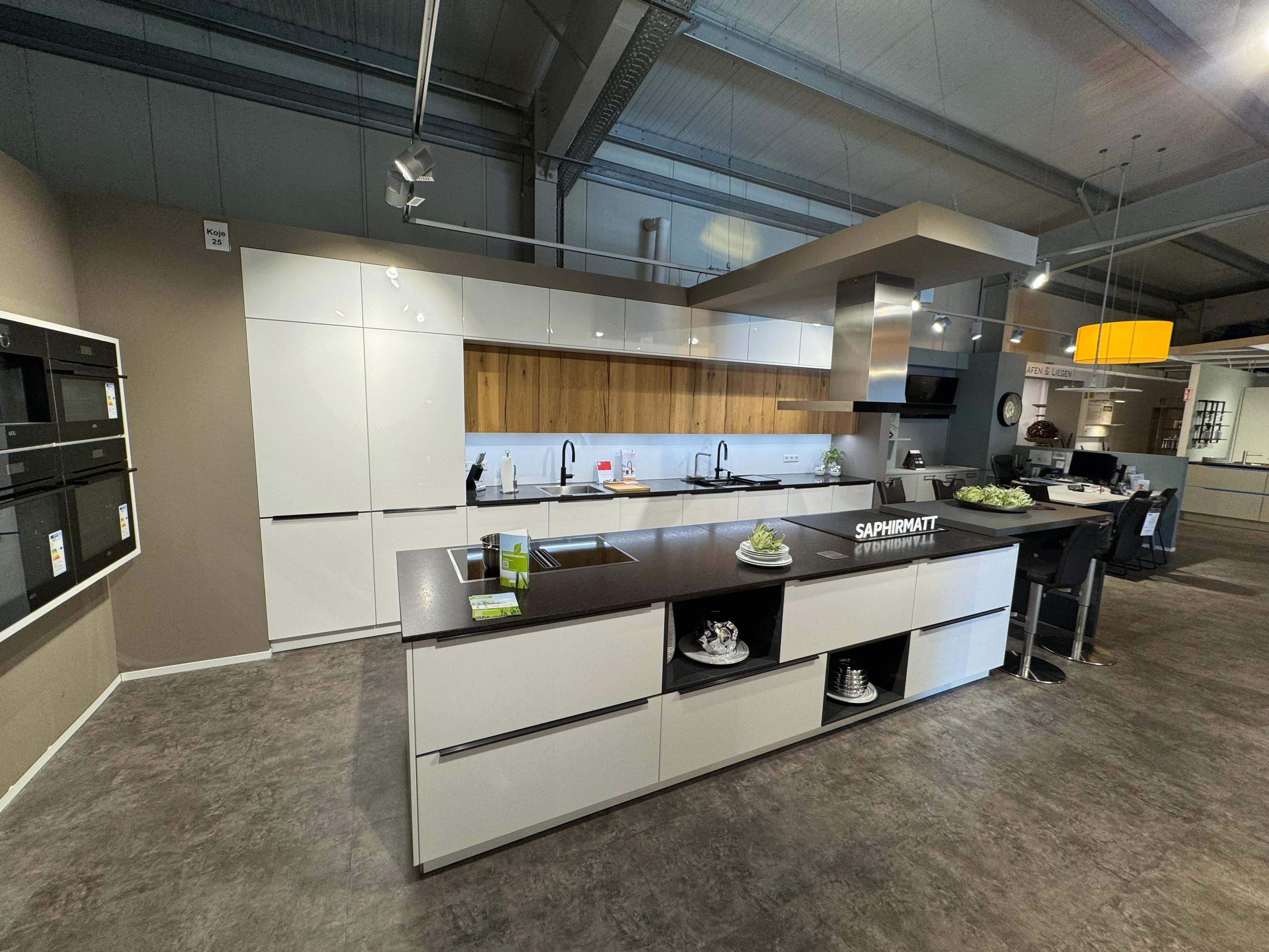 Große Küche in Saphirmatt Weiß mit dunkler Arbeitsplatte, Kochinsel mit Kochfeld und offenen Designfächern, Holz-Nischenrückwand in Eiche, grifflosen Fronten, Deckenlifthaube und integriertem Essplatz mit Barhockern.