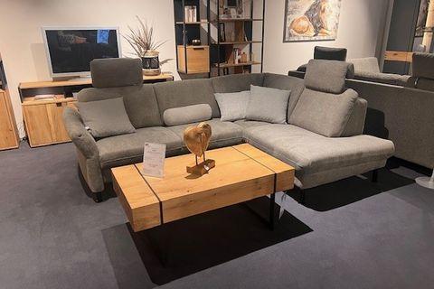 Graue Polstergarnitur mit verstellbaren Kopfstützen, abgestimmten Kissen und einem modernen Couchtisch aus Holz und Metall, arrangiert in einem gemütlichen Wohnraum.