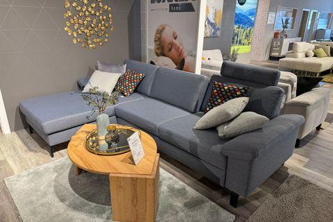 Couchgarnitur in L-Form mit blau-grauem Stoffbezug mit grauen und bunten Kissen