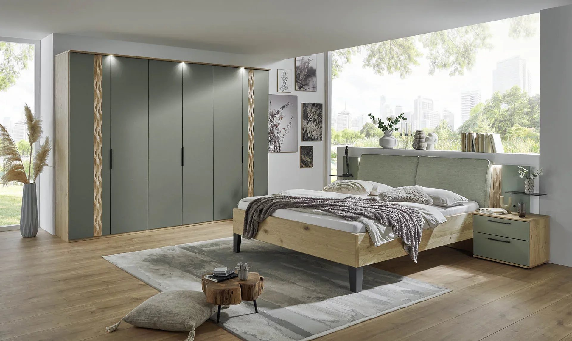 Modernes Schlafzimmer mit einem Bett aus Holz und gepolstertem Kopfteil, einem großen Kleiderschrank mit grünen Türen und dekorativen Akzenten sowie einer breiten Fensterfront mit Blick auf eine grüne Landschaft.