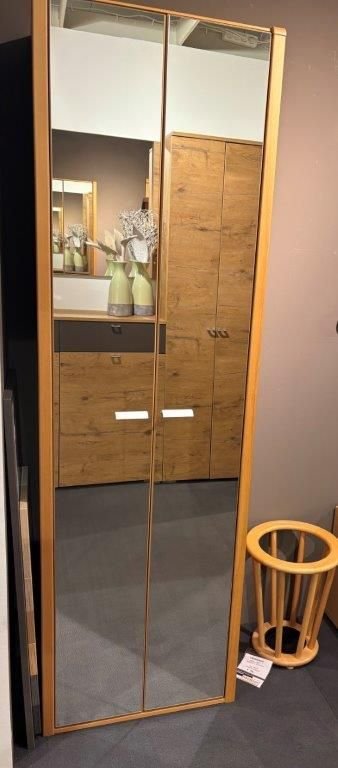 Schuhschrank mit verspiegelten Türen und warmem Holzrahmen, ausgestellt in einem modernen Wohnraum.