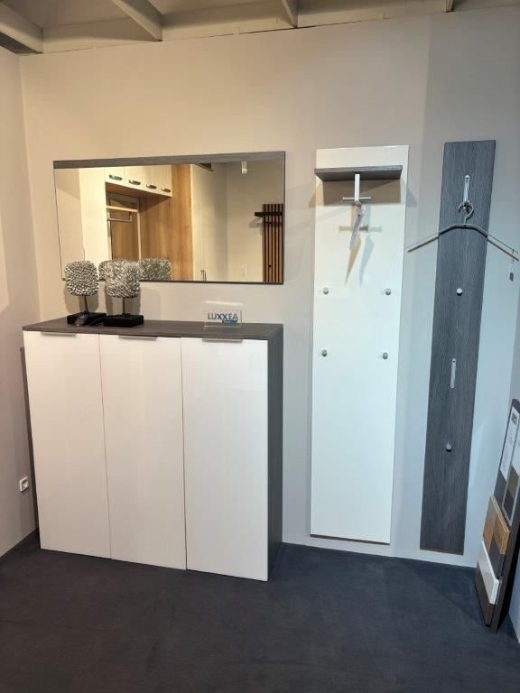 Moderne Garderobe mit weißem Hochglanzschrank, Spiegel und Wandpaneelen mit Kleiderhaken in Weiß und Grau.