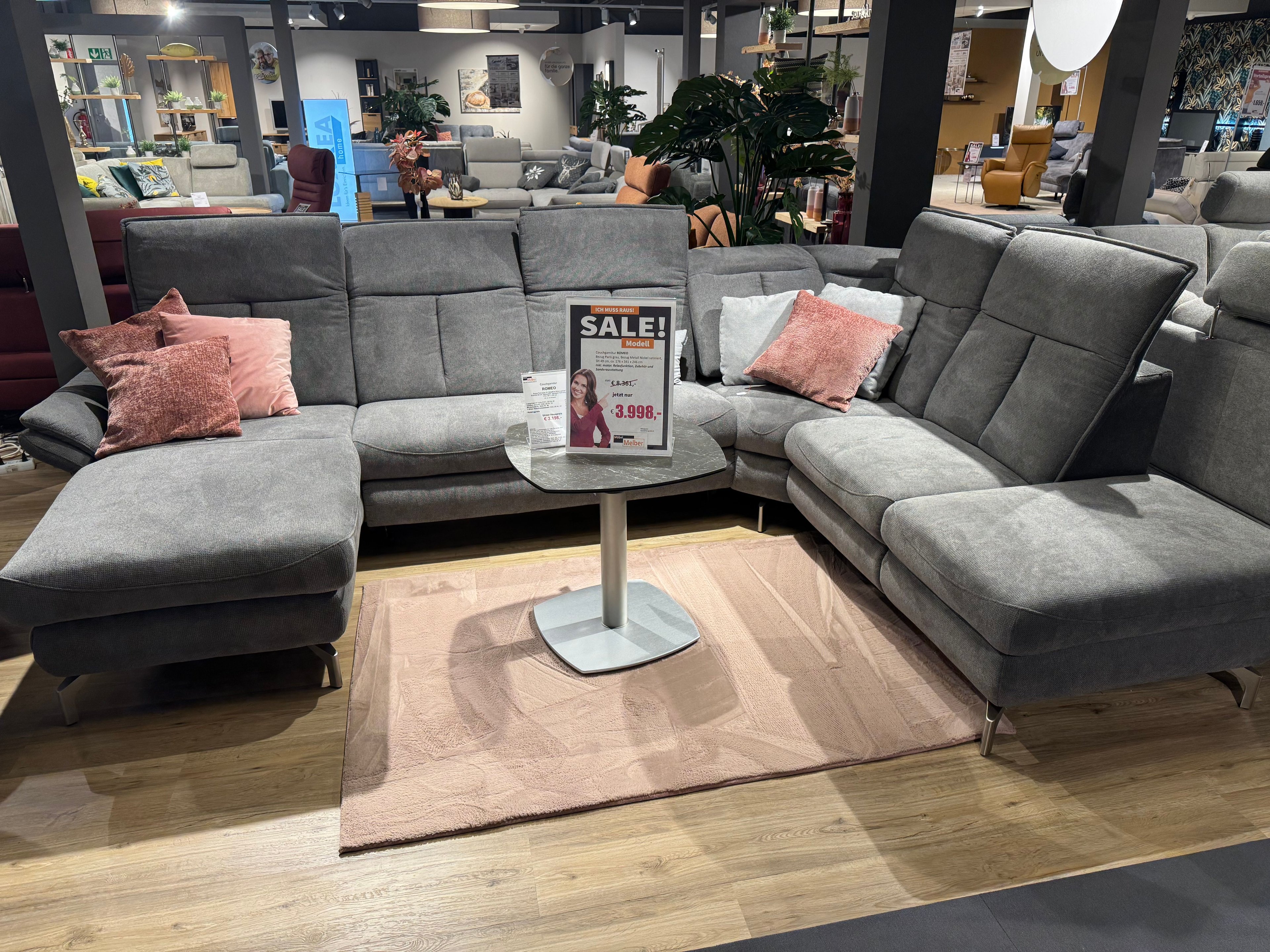 Sofa in U-Form mit grauem Bezug rosanen und grauen Kissen