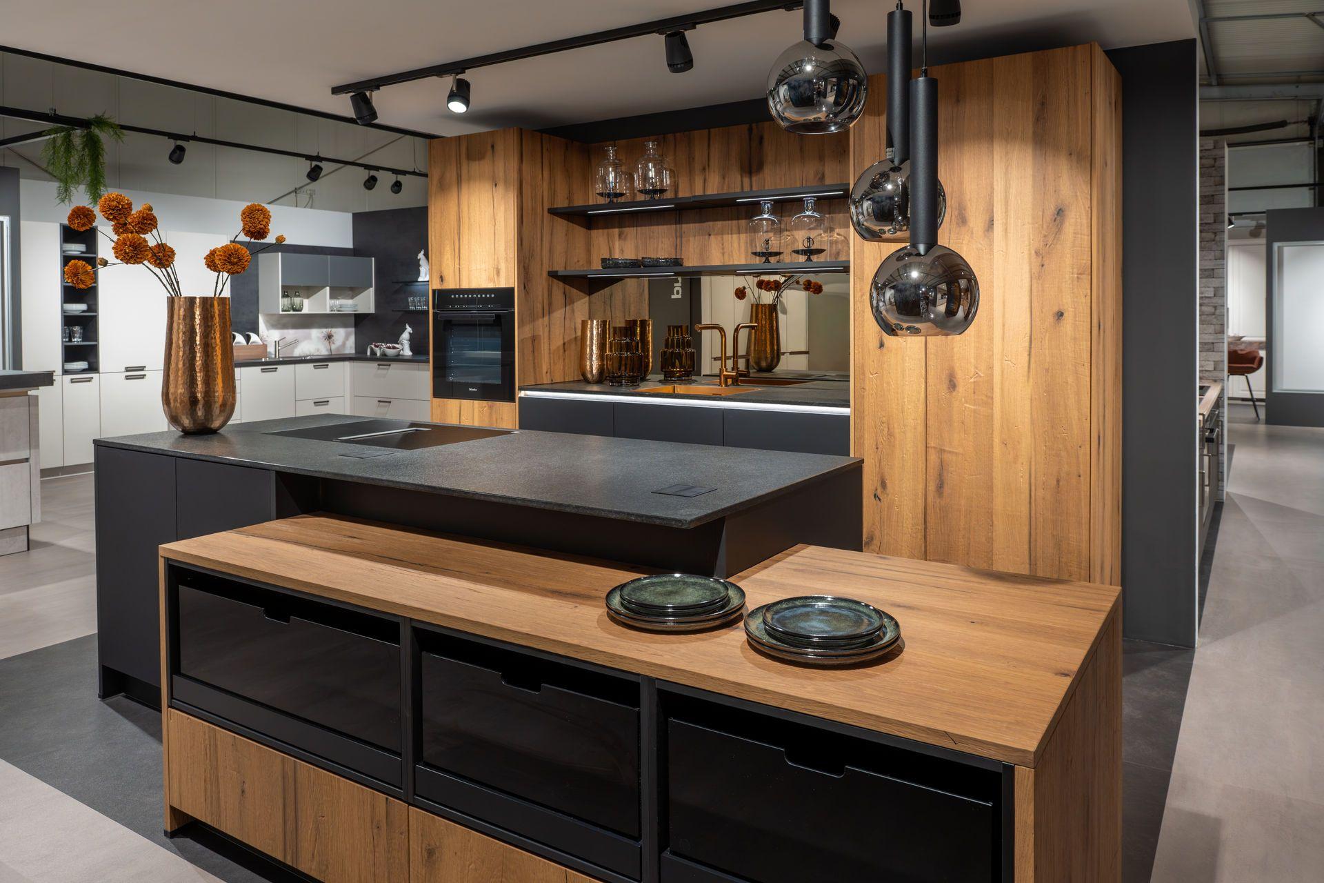 Kochinsel in Anthrazit mit Eichen-Sideboard, verspiegelter Nische, offenen Regalen und Kugel-Pendelleuchten.