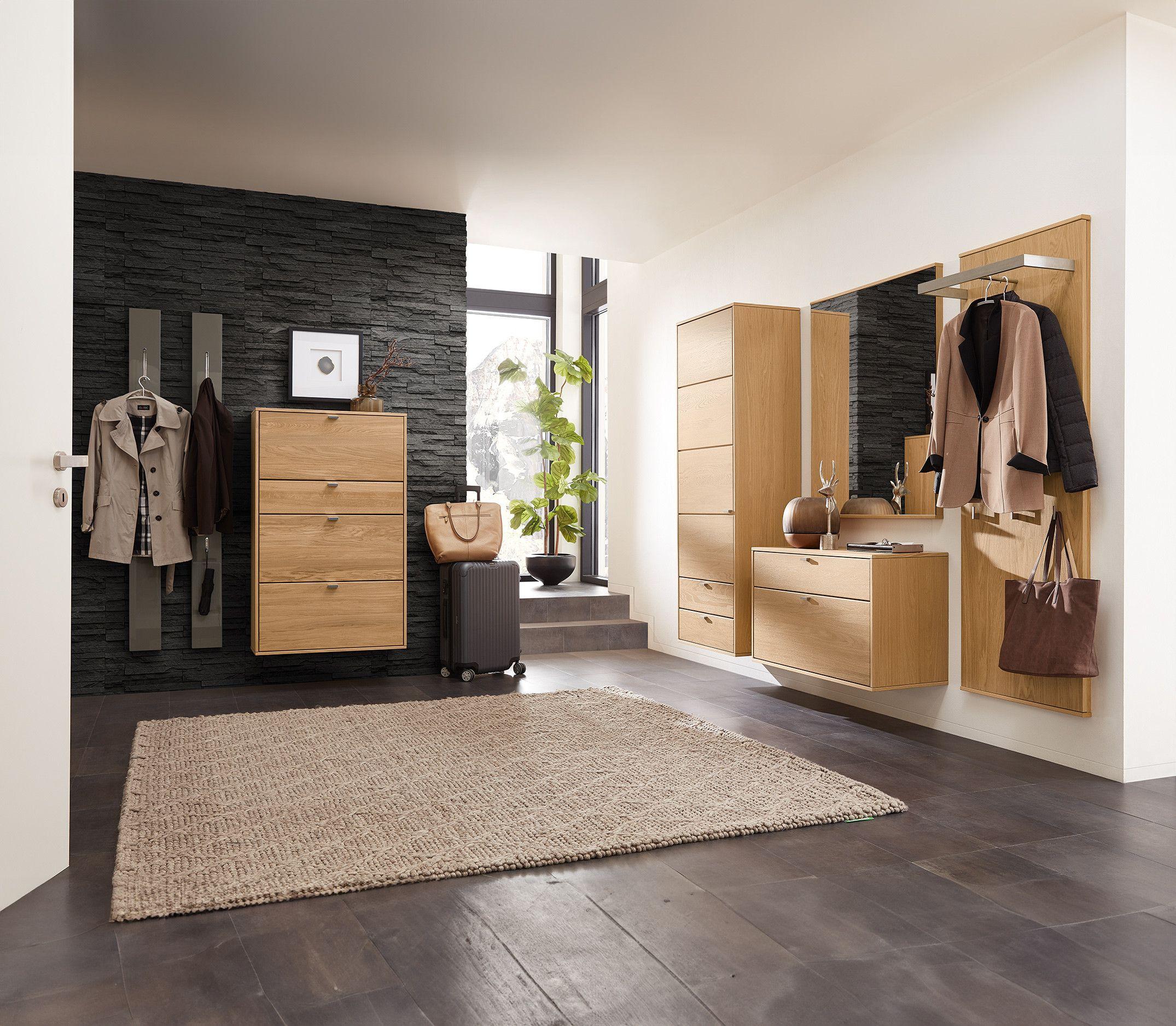 Eingangsbereich mit moderner Holz-Garderobe, Spiegel und Kommoden, ergänzt durch eine dunkle Steinwand. Eingangsbereich mit moderner Holz-Garderobe, Spiegel und Kommoden, ergänzt durch eine dunkle Steinwand.