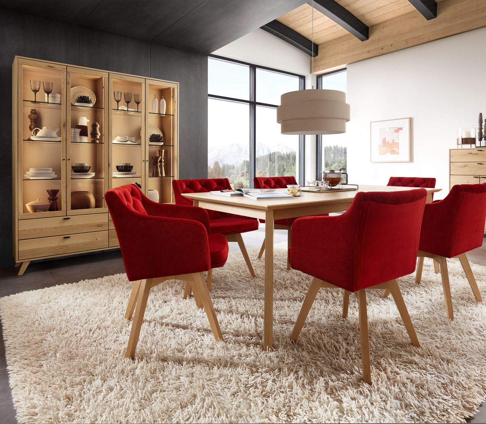 Essbereich mit roten Stühlen und einer beleuchteten Vitrine aus Holz in einem stilvollen Ambiente.