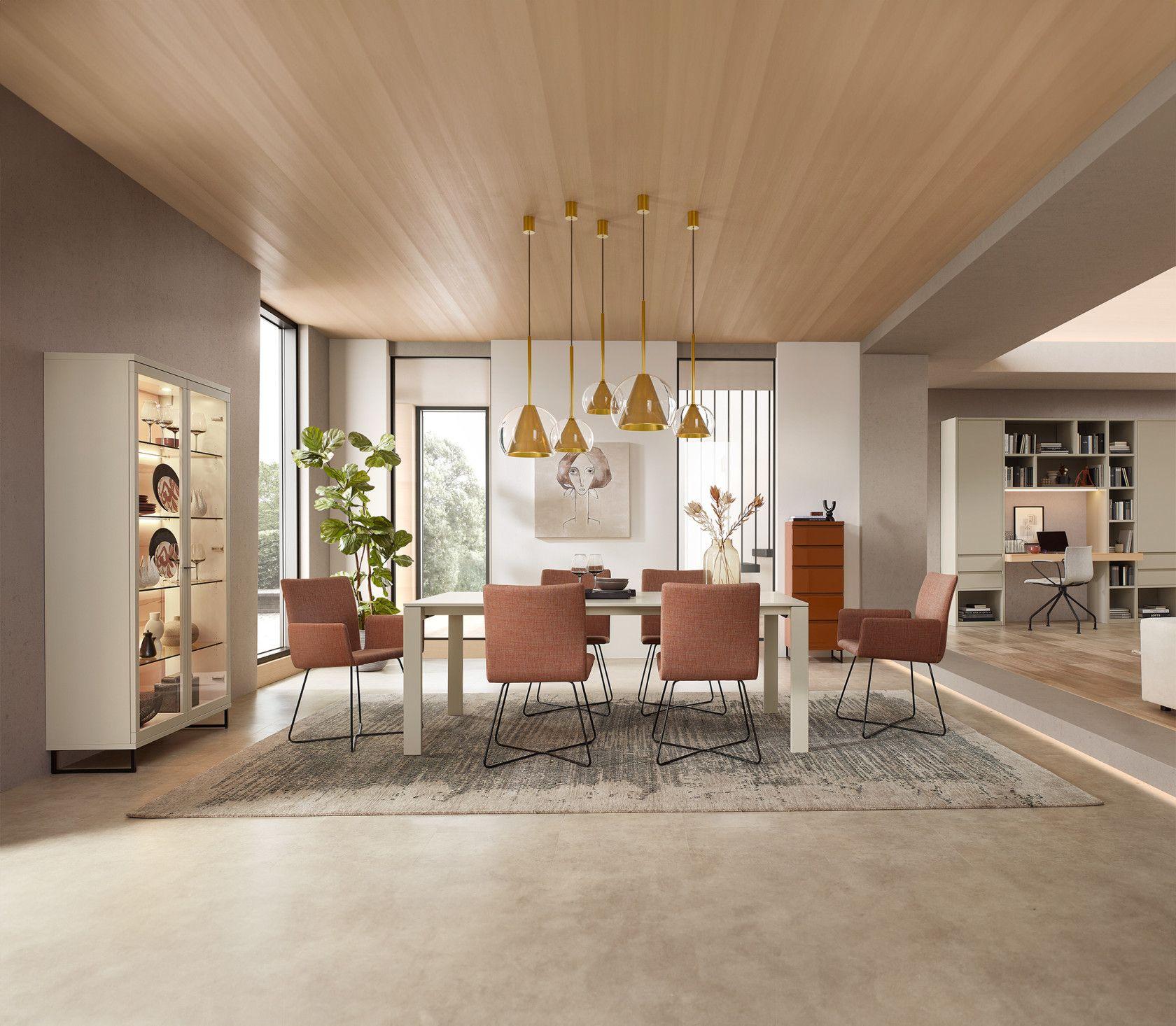 Stilvolle Esszimmermöbel in einem hellen, modernen Raum mit goldenen Pendelleuchten und einer Vitrine im Hintergrund.