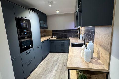 U-förmige Küche in mattem Petrolblau mit Holzarbeitsplatte in Eiche-Optik, dunklen Metro-Fliesen als Nischenrückwand, schwarzer Armatur, Hochschrank mit Einbaugeräten und offenem Metallregal mit Holzböden.