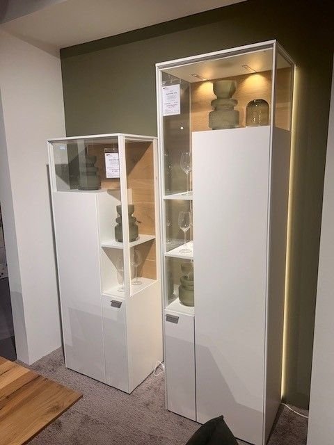 weiße Vitrinen mit asymmetrische Glasgestaltung und verschiedenen Höhen