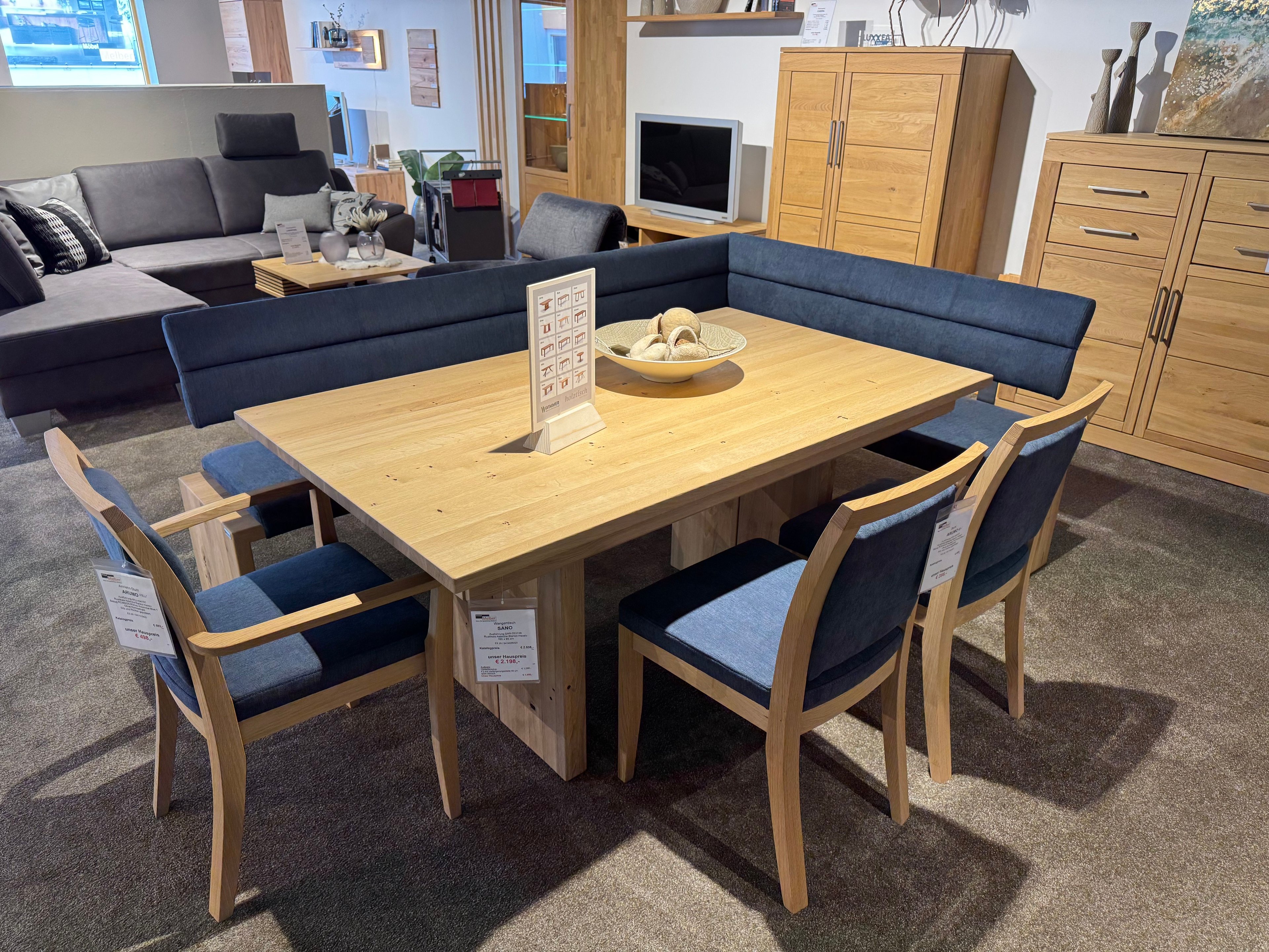 Essgruppe aus Holz mit einer Eckbank und drei Stühlen mit blauem Stoffbezug
